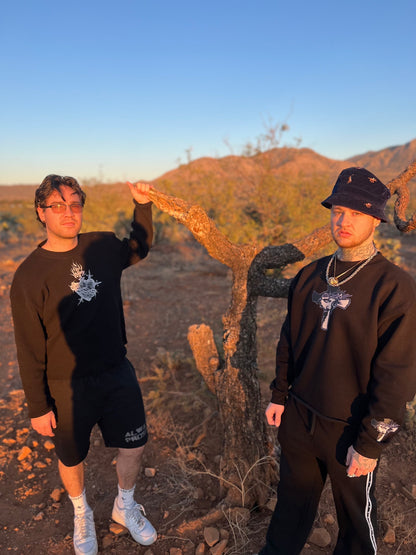 Two models in the desert at sunset wearing the Cold Hearts thermal and the Trinity crewneck
