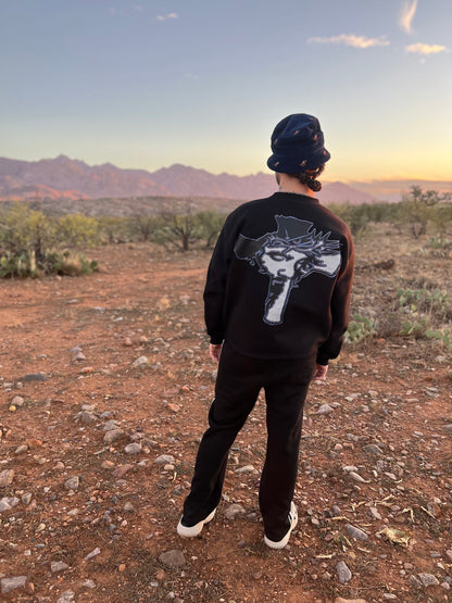 Cross graphic on the back of the Always Prosper Trinity crewneck, worn in the desert at sunset