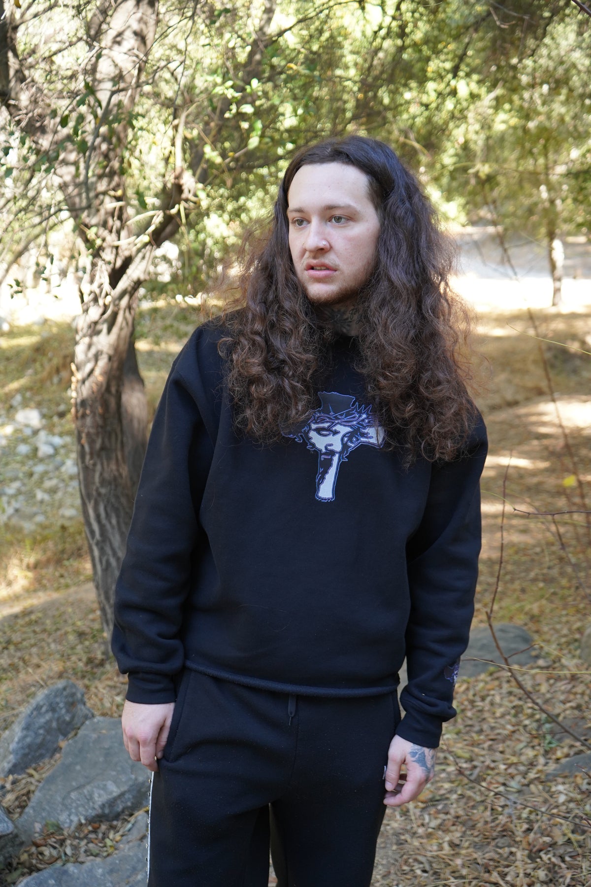 Model wearing the Always Prosper Trinity black crewneck with its cross graphic on the chest