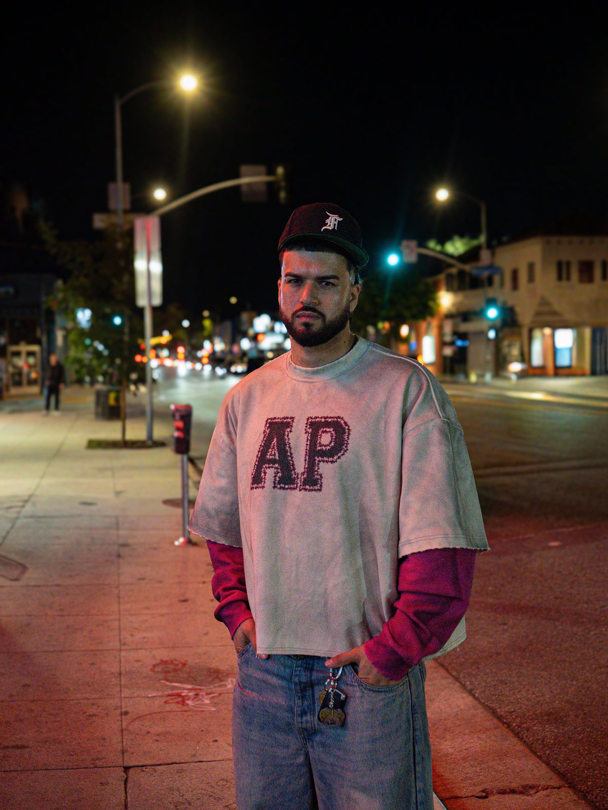 Model wearing the Always Prosper AP University longsleeve on a city street corner at night